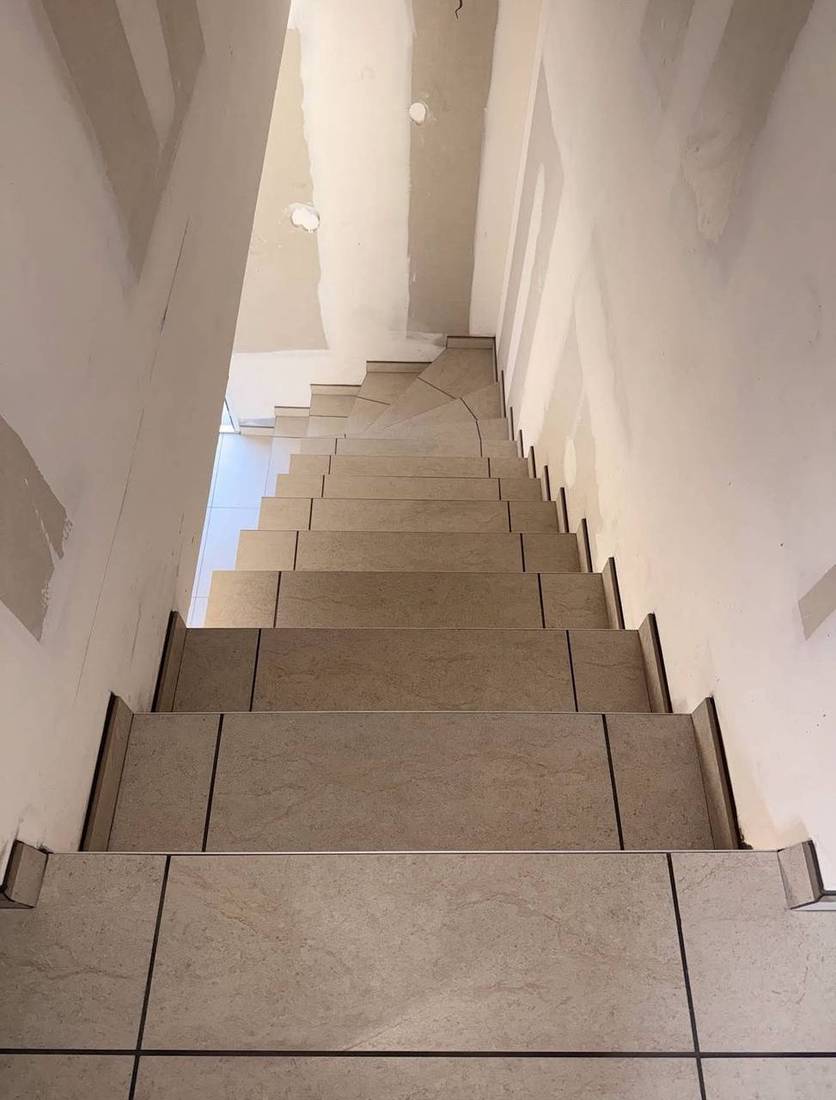 Escalier quart tournant en carrelage beige avec plinthes en crémaillère
